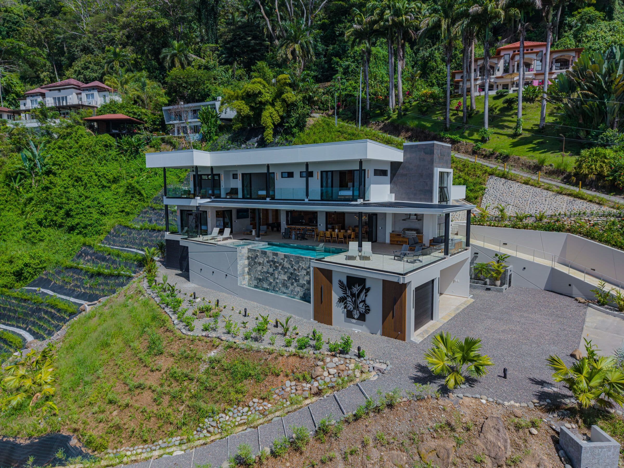 Full facade with pool, deck, and tropical landscaping