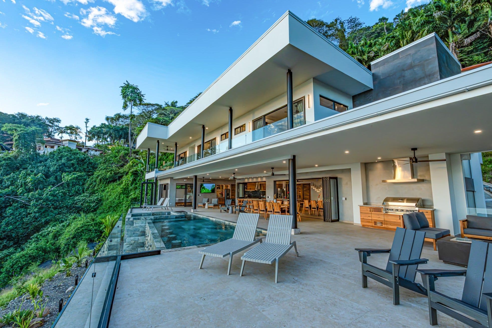 Full facade with pool, deck, and tropical landscaping