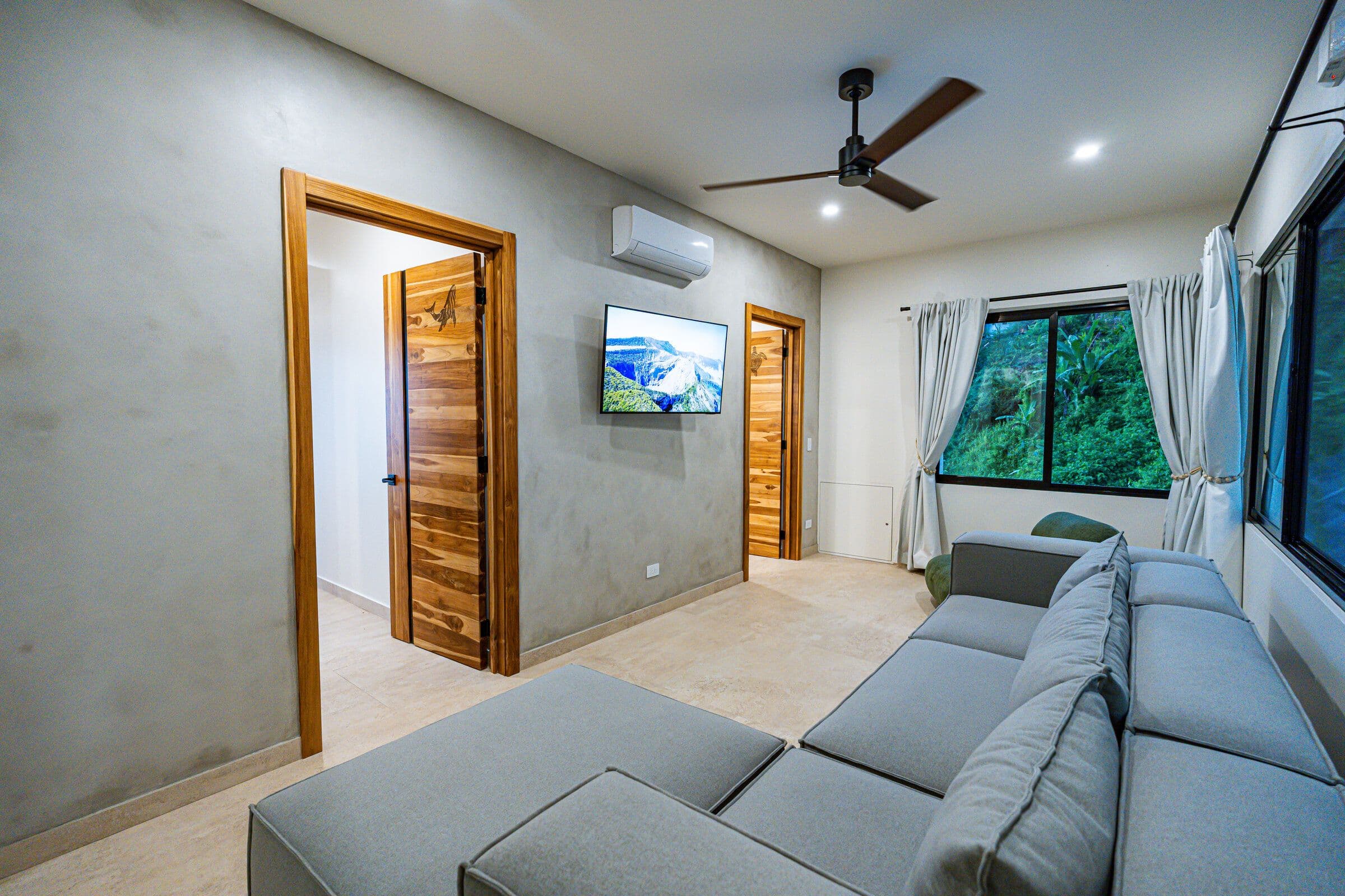 TV room showing TV wall, teak doors, and ceiling fan