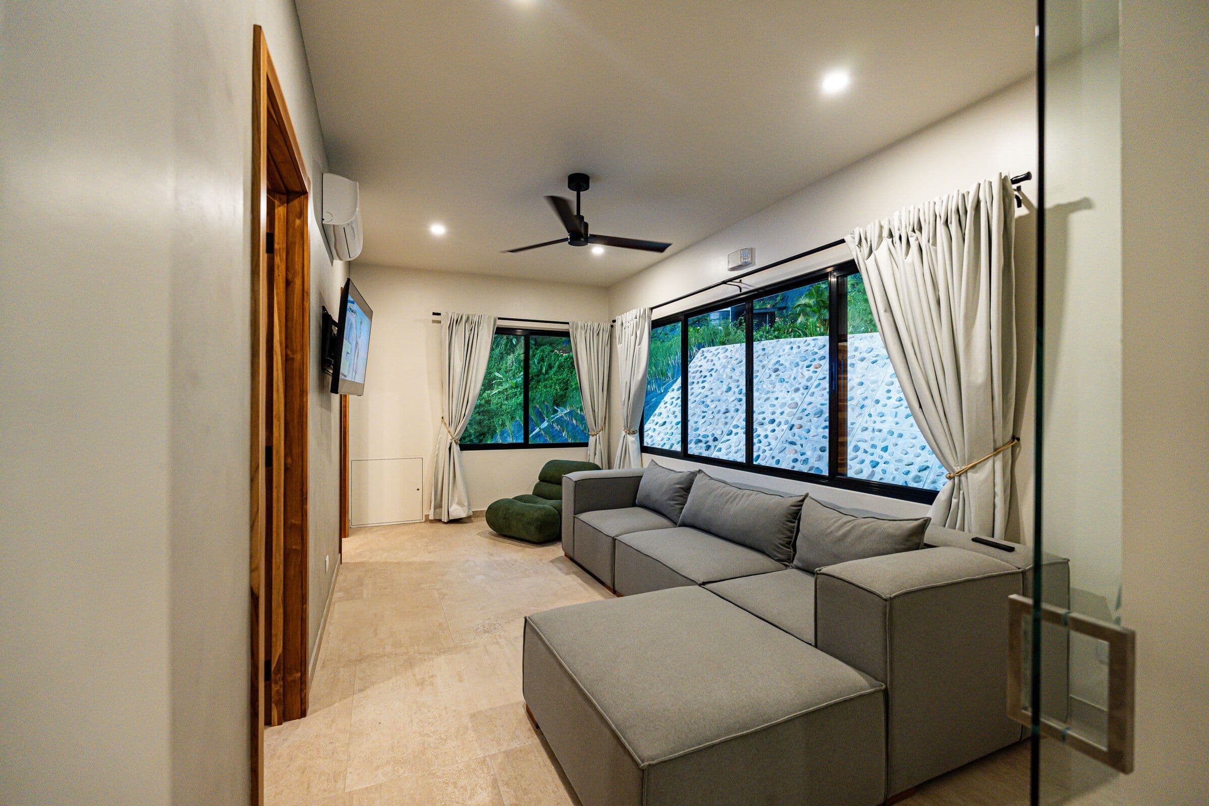 TV room from entry with sectional sofa and stone wall windows