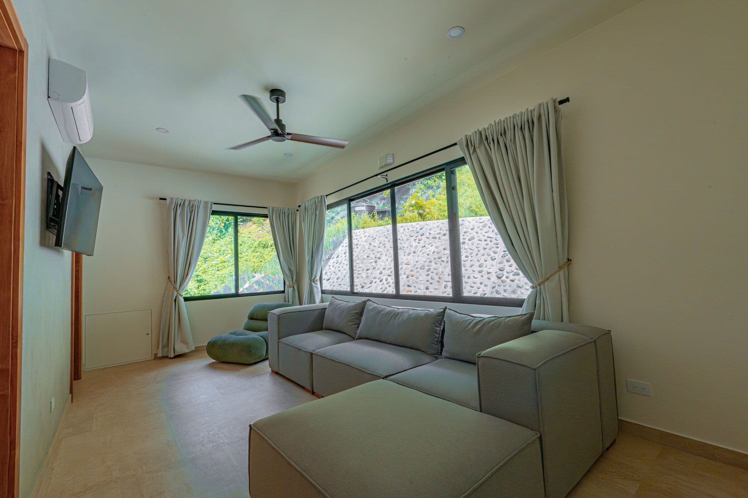 TV room full view with sofa, TV, and stone wall windows